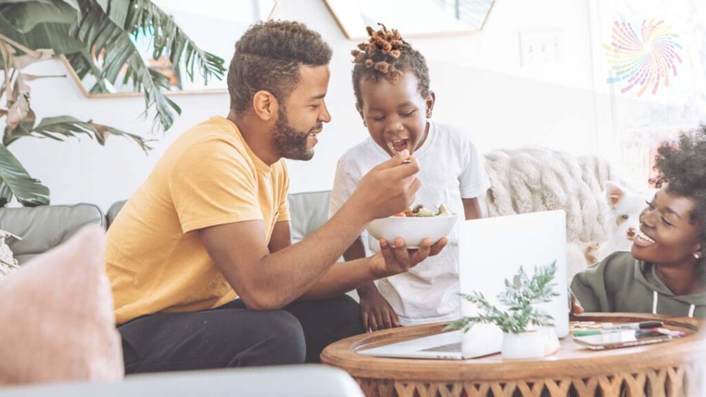 Child with autism who is overcoming picky eating and being fed healthy foods by his dad.